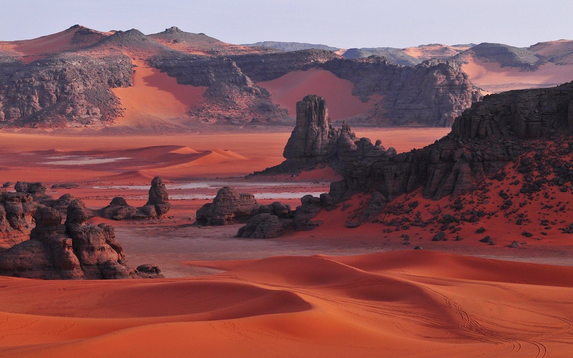 مسافر يقف على كثبان الصحراء الذهبية وقت الغروب